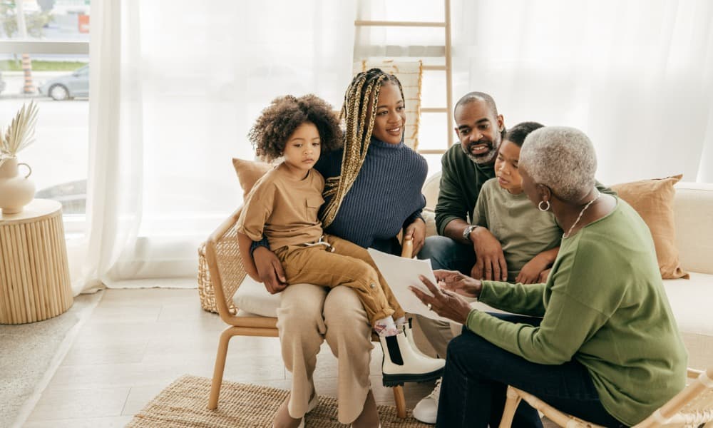 multiple generations of a family sitting together and looking over a document ensuring their multigenerational wealth management plan is in place and adhered to